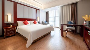 Hotellihuone, jossa on suuri sänky, yöpöydät, työpöytä ja tuoli.