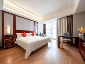 Una habitación de hotel con una cama grande, mesitas de noche, un escritorio y una silla.