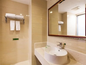 Un baño con un espejo grande, un lavabo y un perchero con dos toallas.