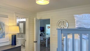 Ein Zimmer mit einem Kinderbett, einer an der Wand befindlichen Karte, einer Lampe und einer Tür zu einem weiteren Raum.