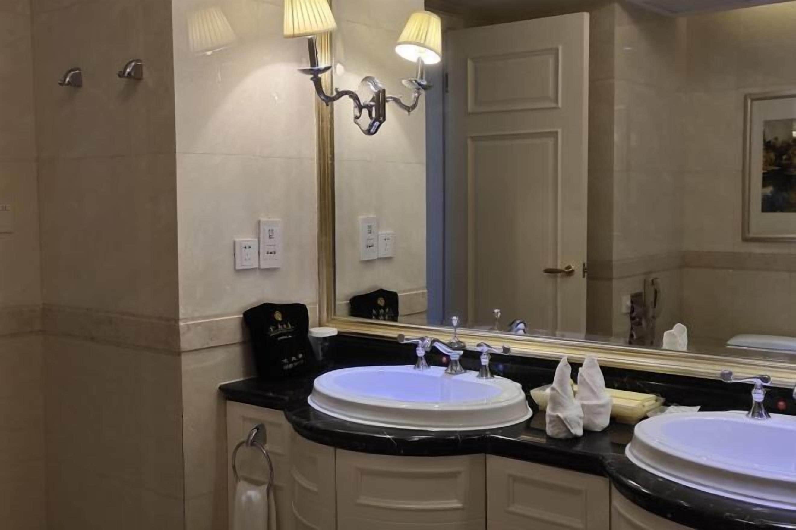 A bathroom with two sinks, a large mirror, and a towel rack.
