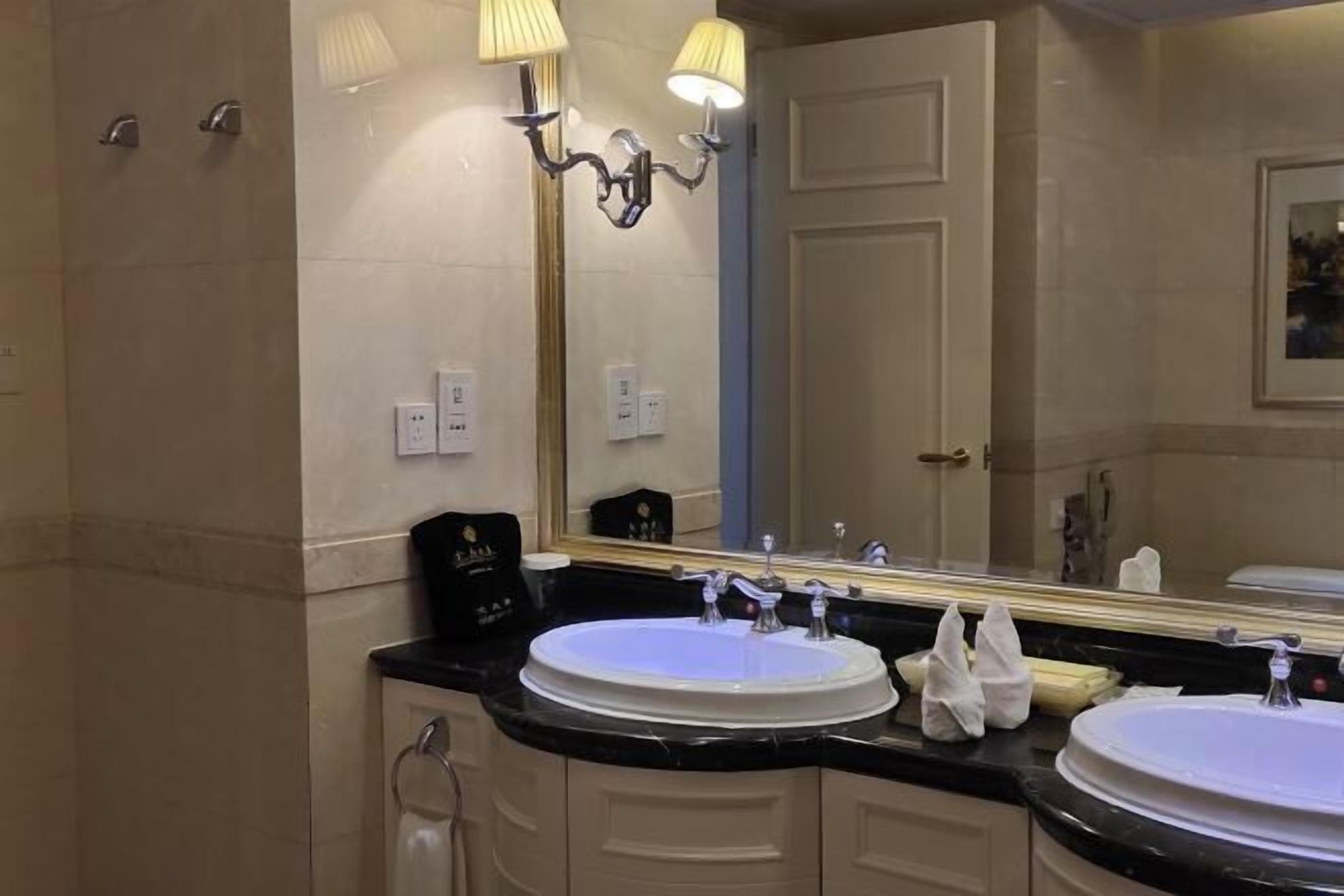 A bathroom with two sinks, a large mirror, and a shower.