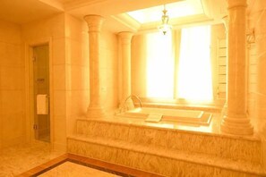 Une salle de bain dotée d’une baignoire, d’une douche et d’une porte en verre donnant accès à un dressing.