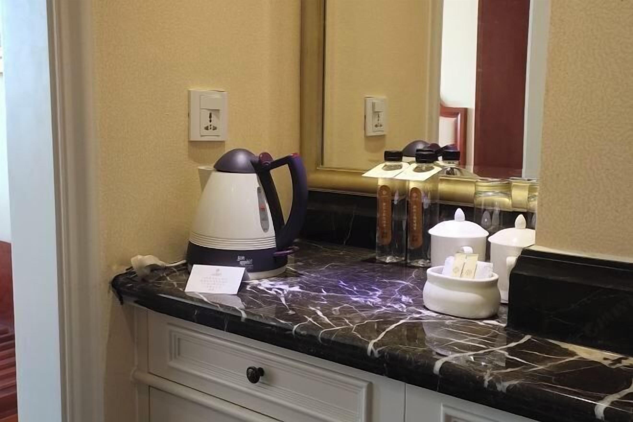 Et badeværelse på et hotel med bordplade i marmor, kaffemaskine, spejl og toiletartikler.