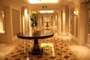 Un couloir d’hôtel avec une table ronde, des colonnes et un sol à motifs.