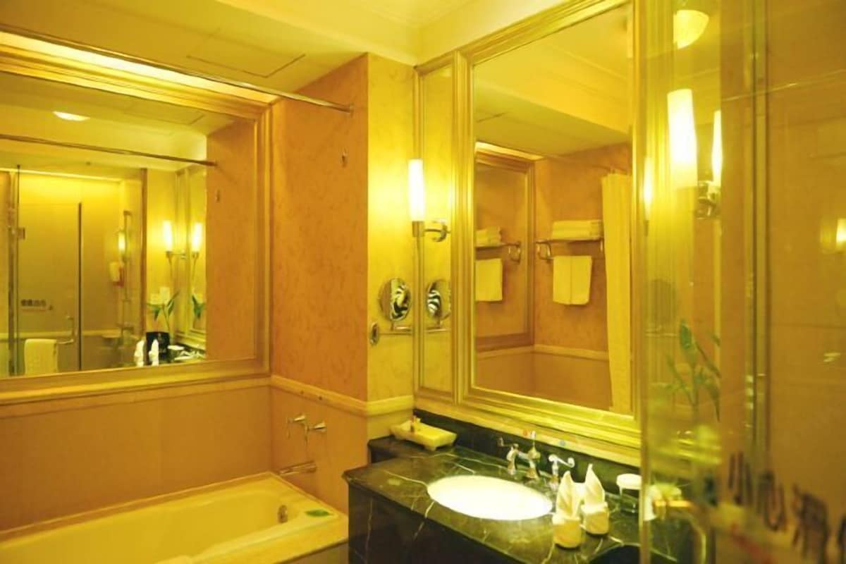 Une salle de bain d’hôtel avec un grand miroir, une baignoire, un lavabo et un meuble-lavabo.