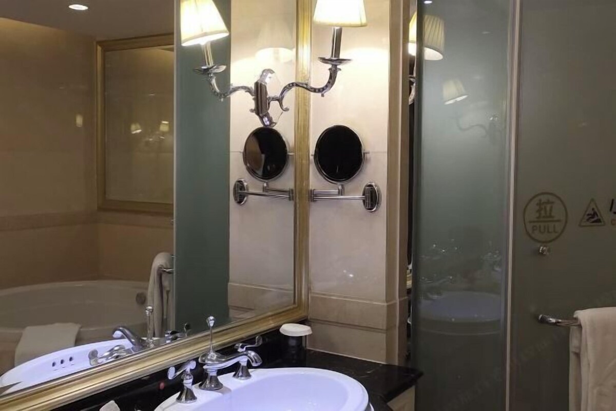 Une salle de bain dotée d’un grand miroir, d’un lavabo, d’une baignoire et d’une cabine de douche en verre.