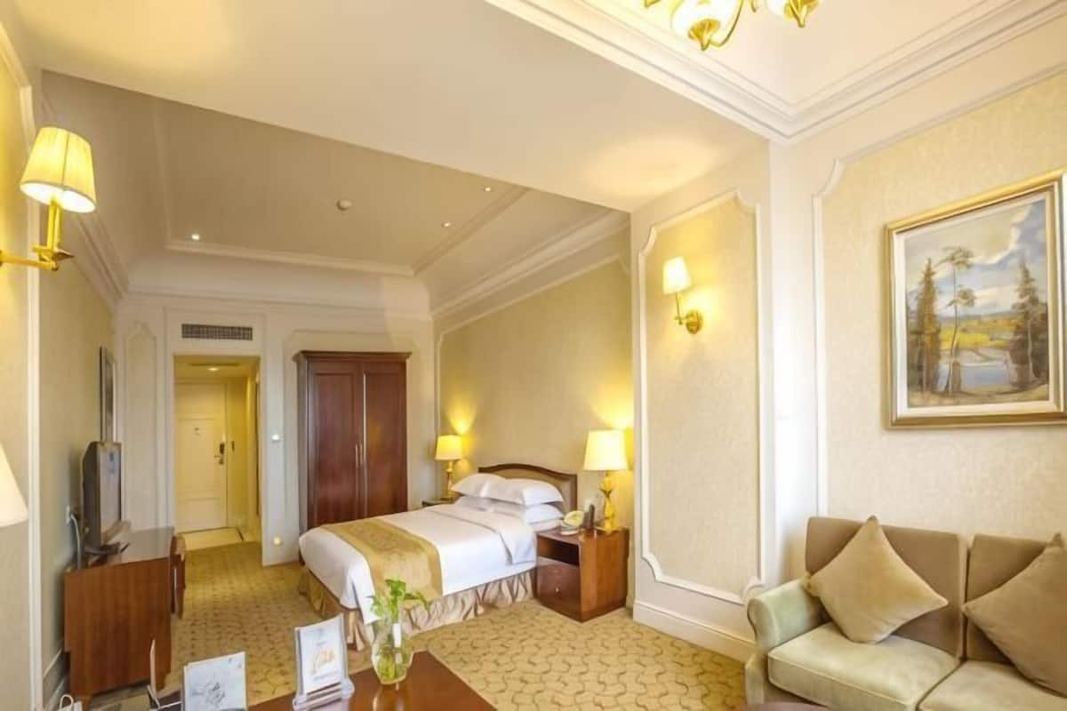 Ein Hotelzimmer mit Bett, Nachttischen, einer Sitzecke, einem Schreibtisch und einem Fernseher.
