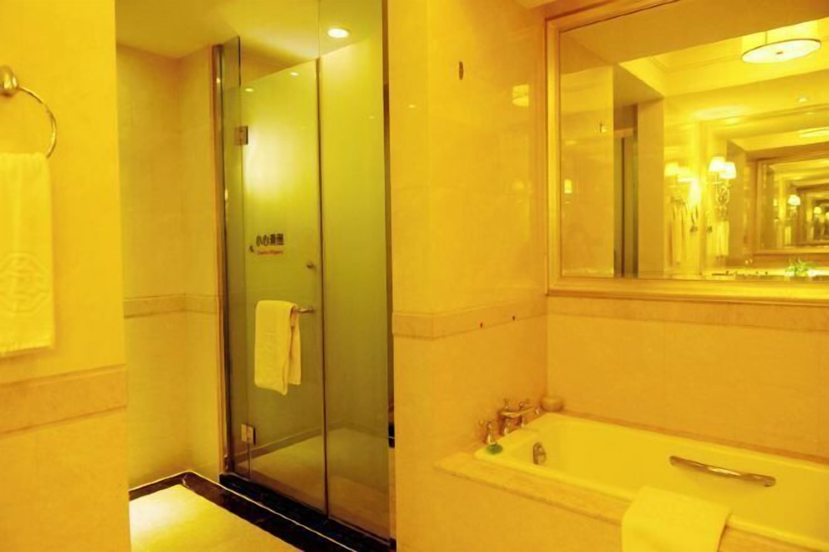 A modern bathroom with a glass-enclosed shower, a large mirror, and a bathtub.