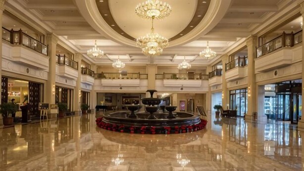 A spacious lobby with a central fountain, multiple balconies, and a polished marble floor.