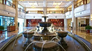A multi-tiered fountain in a spacious lobby with chandeliers, a high ceiling, and a modern architectural design.