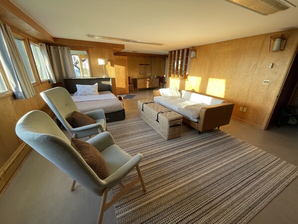 Ein modernes Hotelzimmer mit einem Bett, einer Couch, einem Sessel und einem kleinen Tisch.