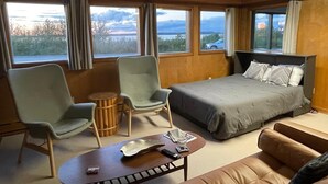 A room with a bed, two armchairs, a small table, and a sofa.