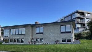 A modern two-story house with large windows, a flat roof, and a well-maintained lawn.