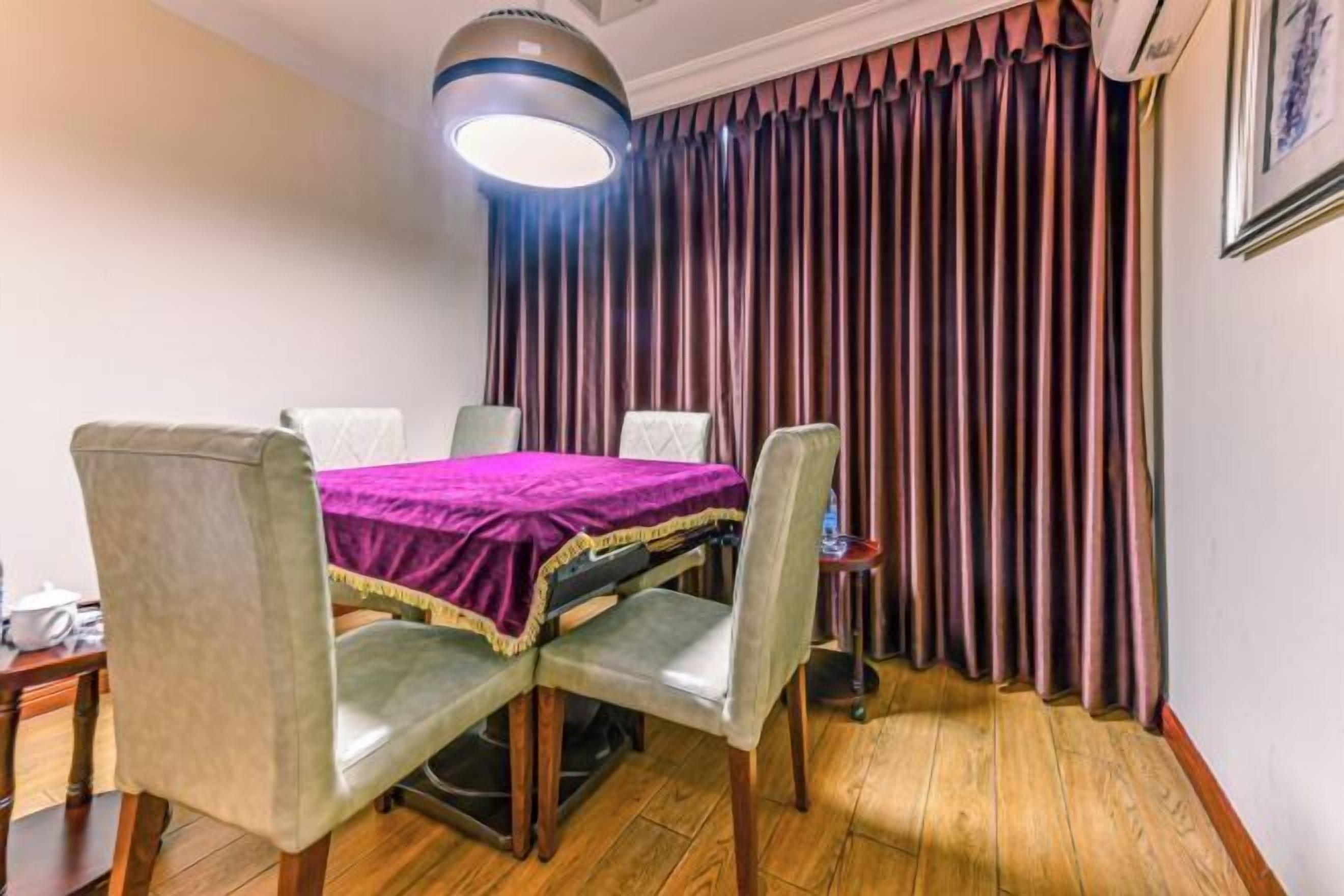 Comedor con una mesa dispuesta para cuatro personas, una lámpara de techo y un fondo de cortina.
