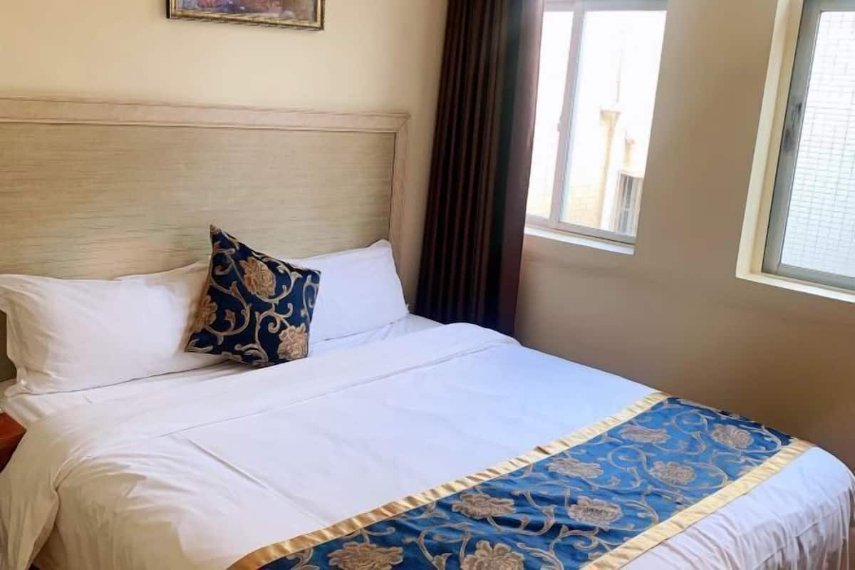 Una cama bien hecha con sábanas blancas y un corredor decorativo azul y dorado.
