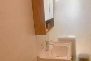 A bathroom with a white sink, a wooden vanity, and a mirror above the sink. - Zhuhai Xilong Apartment (Zhuhai)