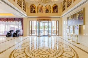A spacious lobby with a polished floor, a grand chandelier, and a set of massage chairs.