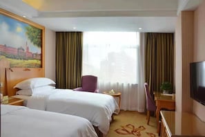 A hotel room with two beds, a television, a desk with a chair, and a painting on the wall.