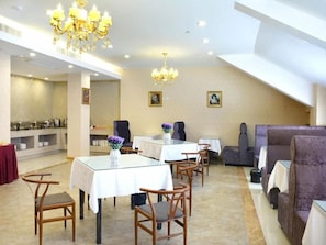 A hotel dining area with tables, chairs, and a chandelier.