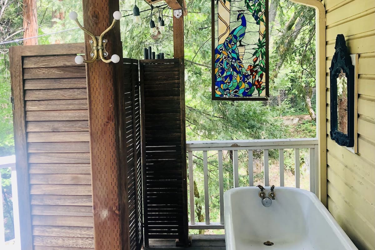 A rustic bathroom with a freestanding bathtub, a wooden door, a peacock stained glass window, and a sign reading "Country Bath".