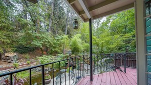 A wooden deck with a metal railing overlooking a garden with a pond and various plants. - Flume's End (Nevada City)