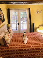A hotel room with a bed, a nightstand, a lamp, and a view through the door.