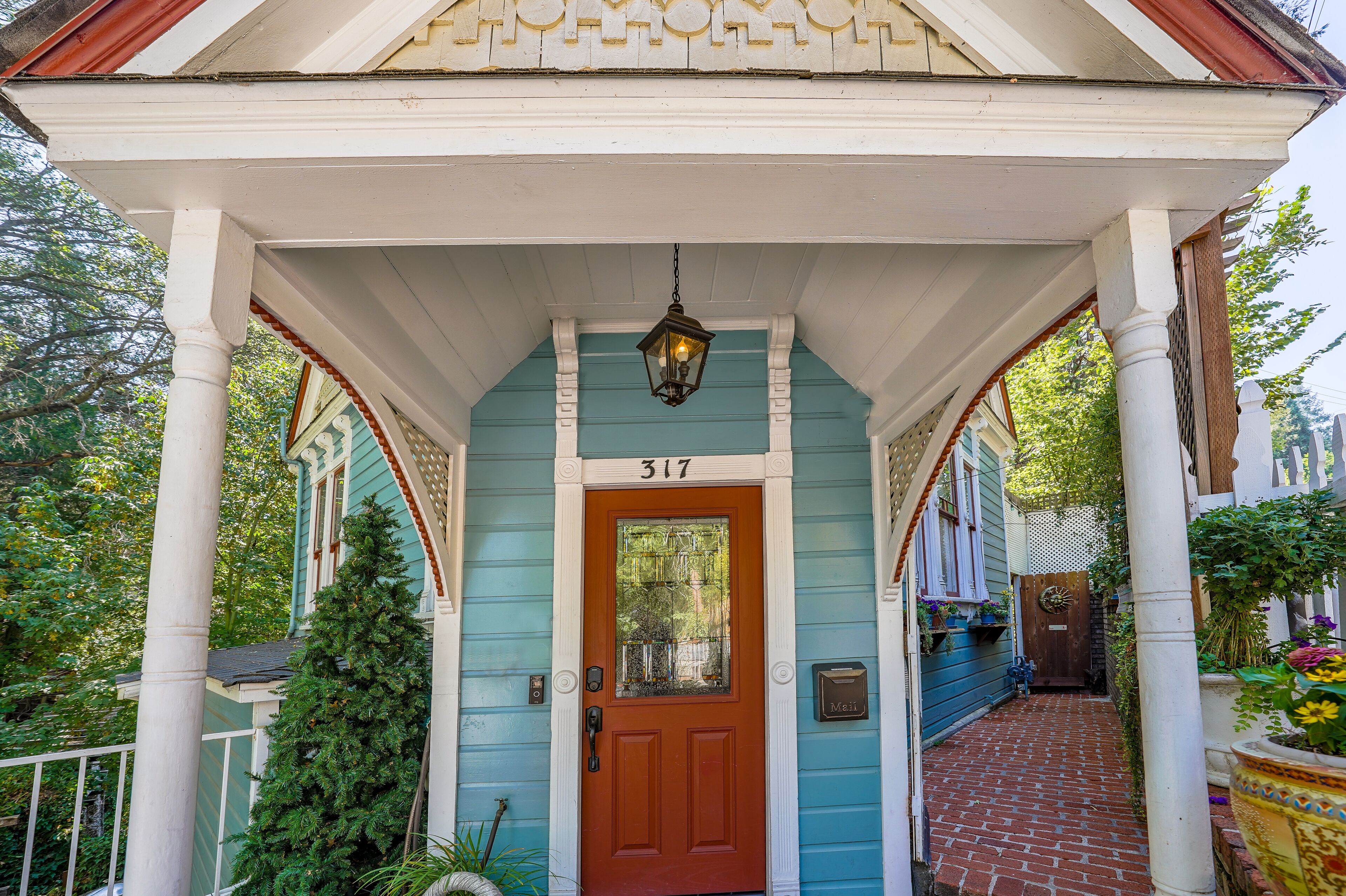 A blue house with the number 317 on the front door, a porch with white columns, and a brick pathway leading to the door.