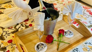 A bed with floral bedding, a bottle of champagne, two glasses, a swan-shaped towel, and a rose. - Flume's End (Nevada City)