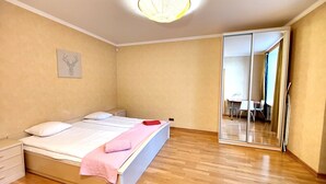 Une chambre à coucher avec un lit, une table de chevet, un miroir et un plancher en bois.