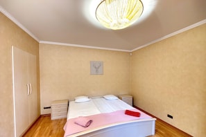 A bedroom with a bed, bedside tables, a wardrobe, and a ceiling light fixture.
