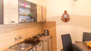 A kitchen with a sink, stove, cabinets, and a dining table with chairs. - Apartments Old Town Aleksici (Budva)