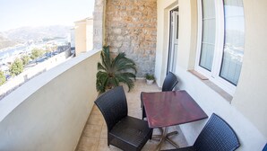 A balcony with a stone wall, a table, two chairs, and a potted plant. - Apartments Old Town Aleksici (Budva)