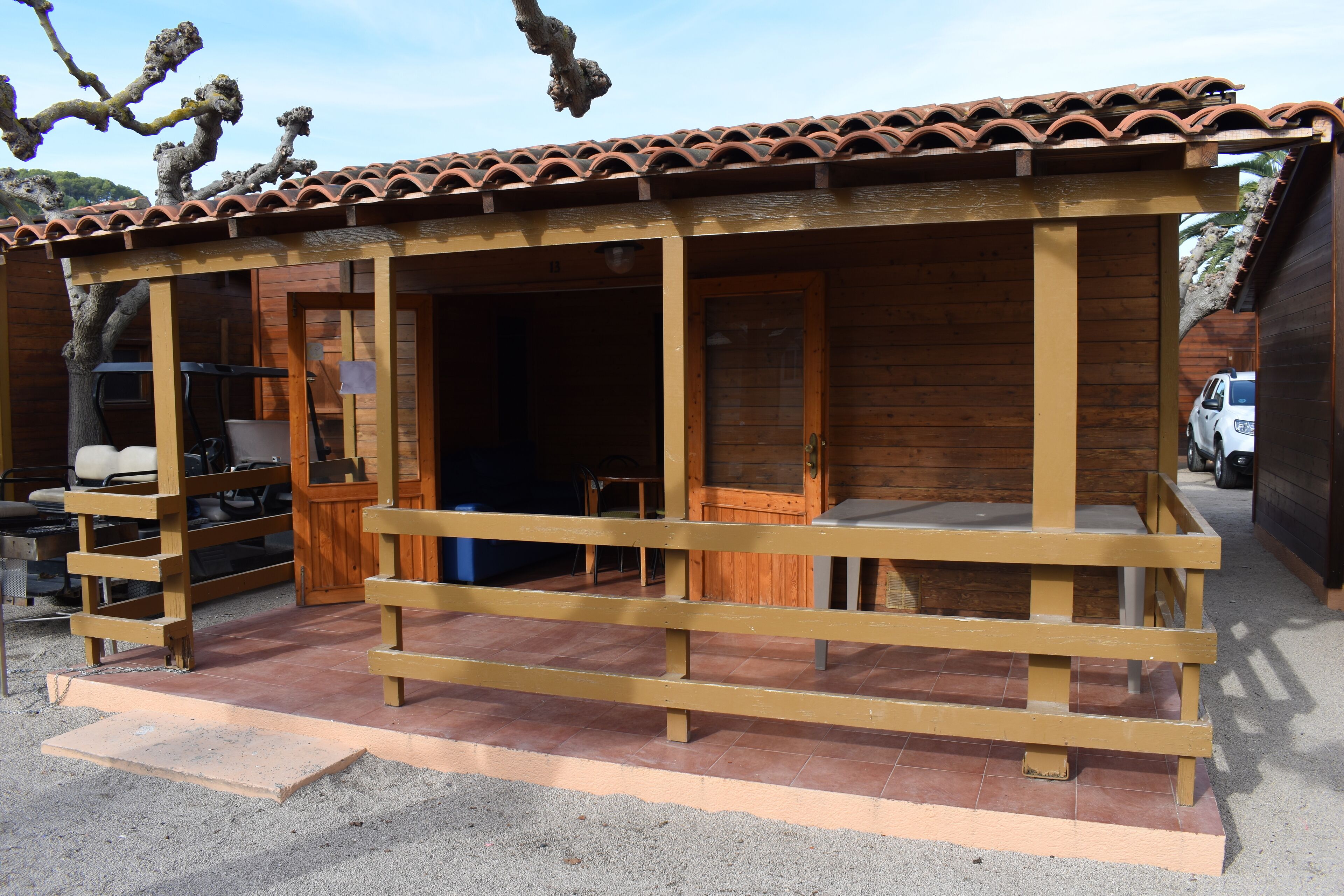 Una cabana de fusta amb teulada d'àmples rajoles, un porxo amb barana de fusta i una porta que dona a l'interior.