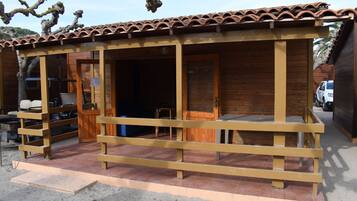 Una cabana de fusta amb teulada d'àmples rajoles, un porxo amb barana de fusta i una porta que dona a l'interior.