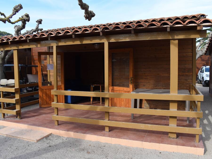 Una cabana de fusta amb teulada d'àmples rajoles, un porxo amb barana de fusta i una porta que dona a l'interior.