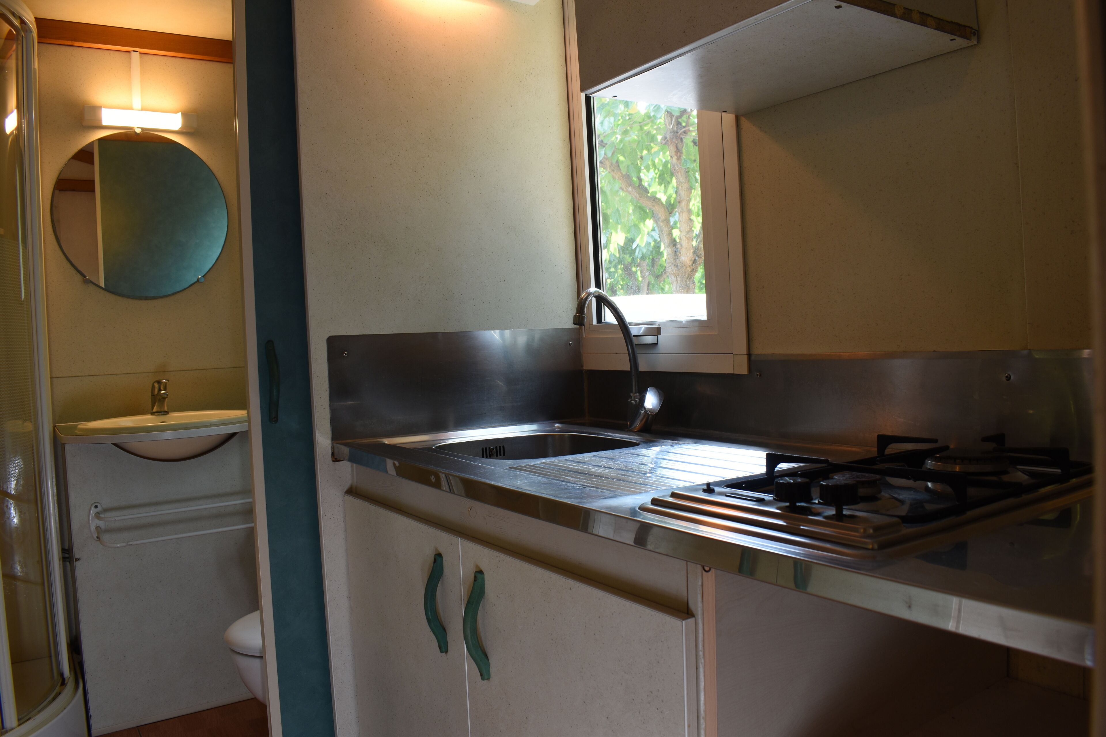 Cocina compacta con lavamanos, estufa y ventana.