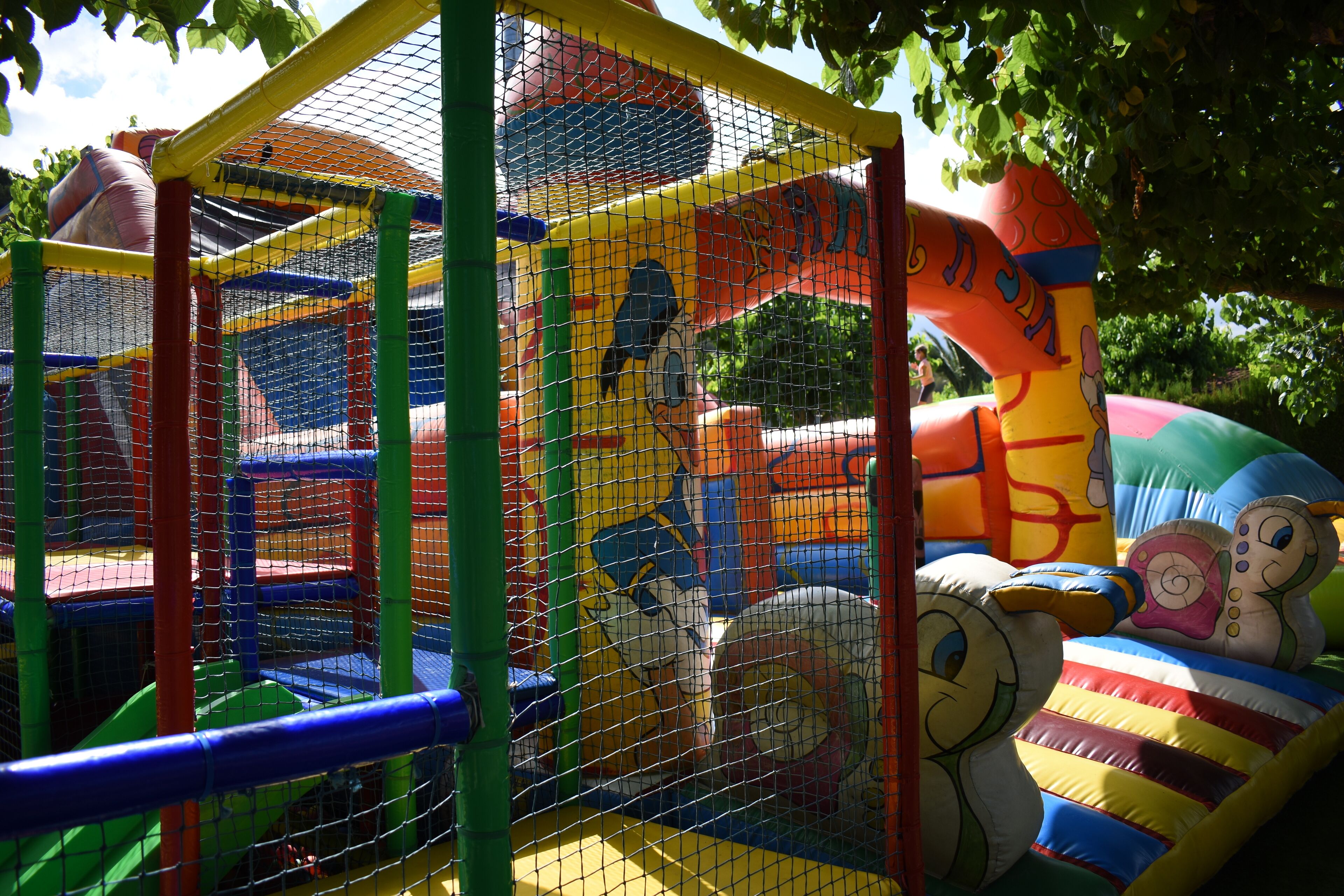 A colorful inflatable play structure with a netted enclosure.