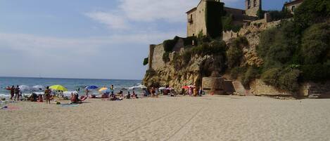 Una playa con un edificio histórico en un acantilado con vista al mar.