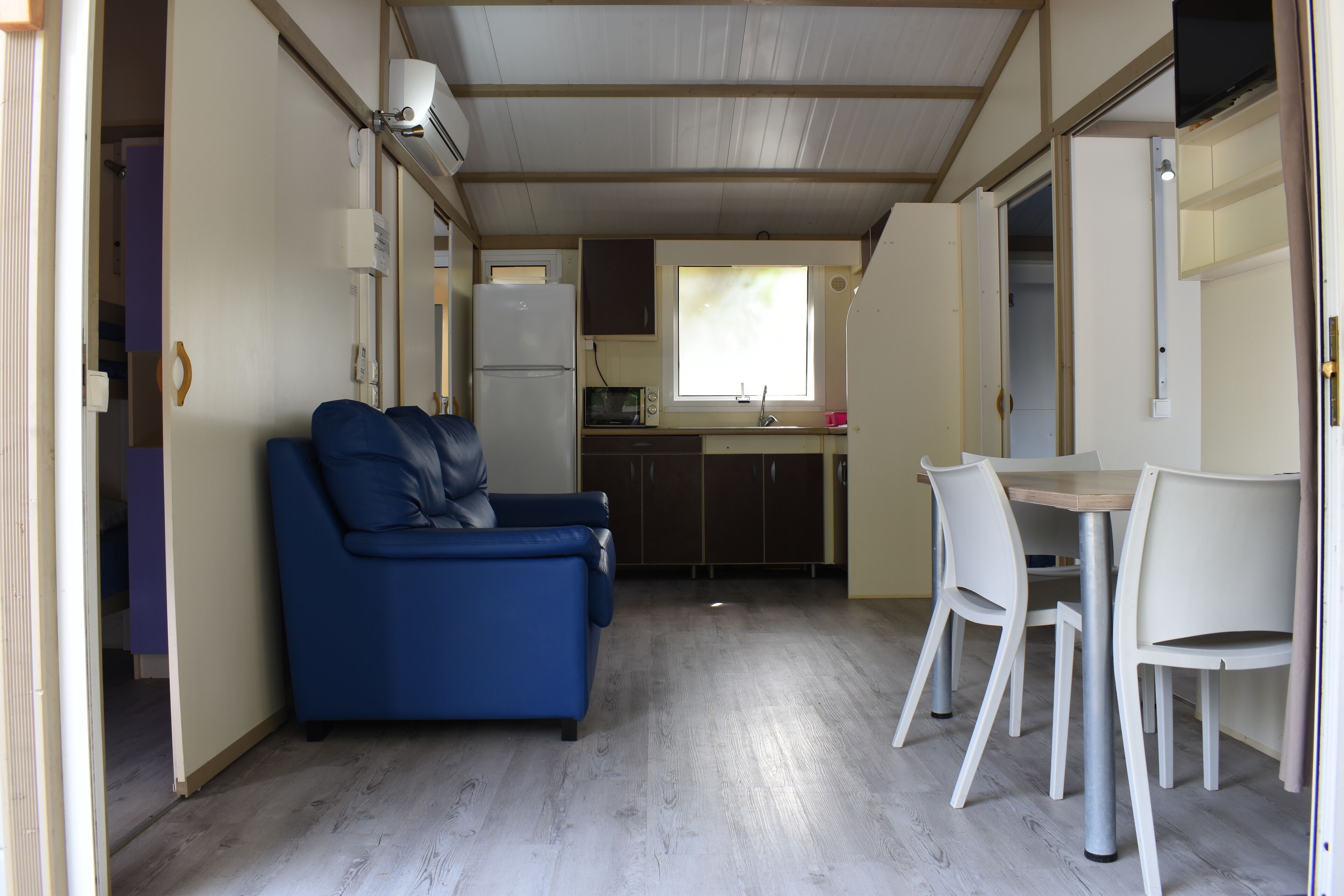 Een knus woongedeelte met een kitchenette, een bank en een eettafel met stoelen.