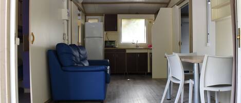 Een knus woongedeelte met een kitchenette, een bank en een eettafel met stoelen.