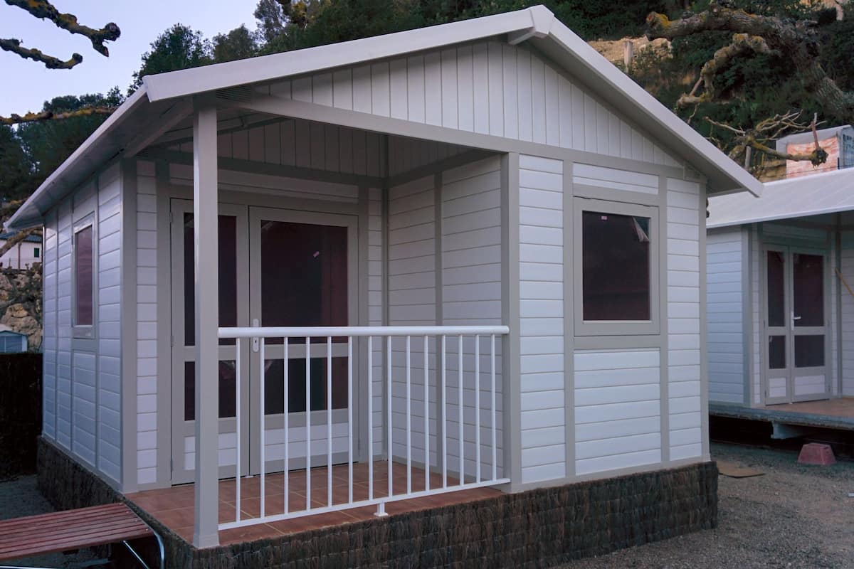 Eine kleine, eingeschossige Holzhütte mit Veranda und kleiner Terrasse.