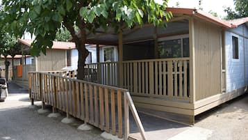 Una casa móvil con terraza de madera y porche cubierto.