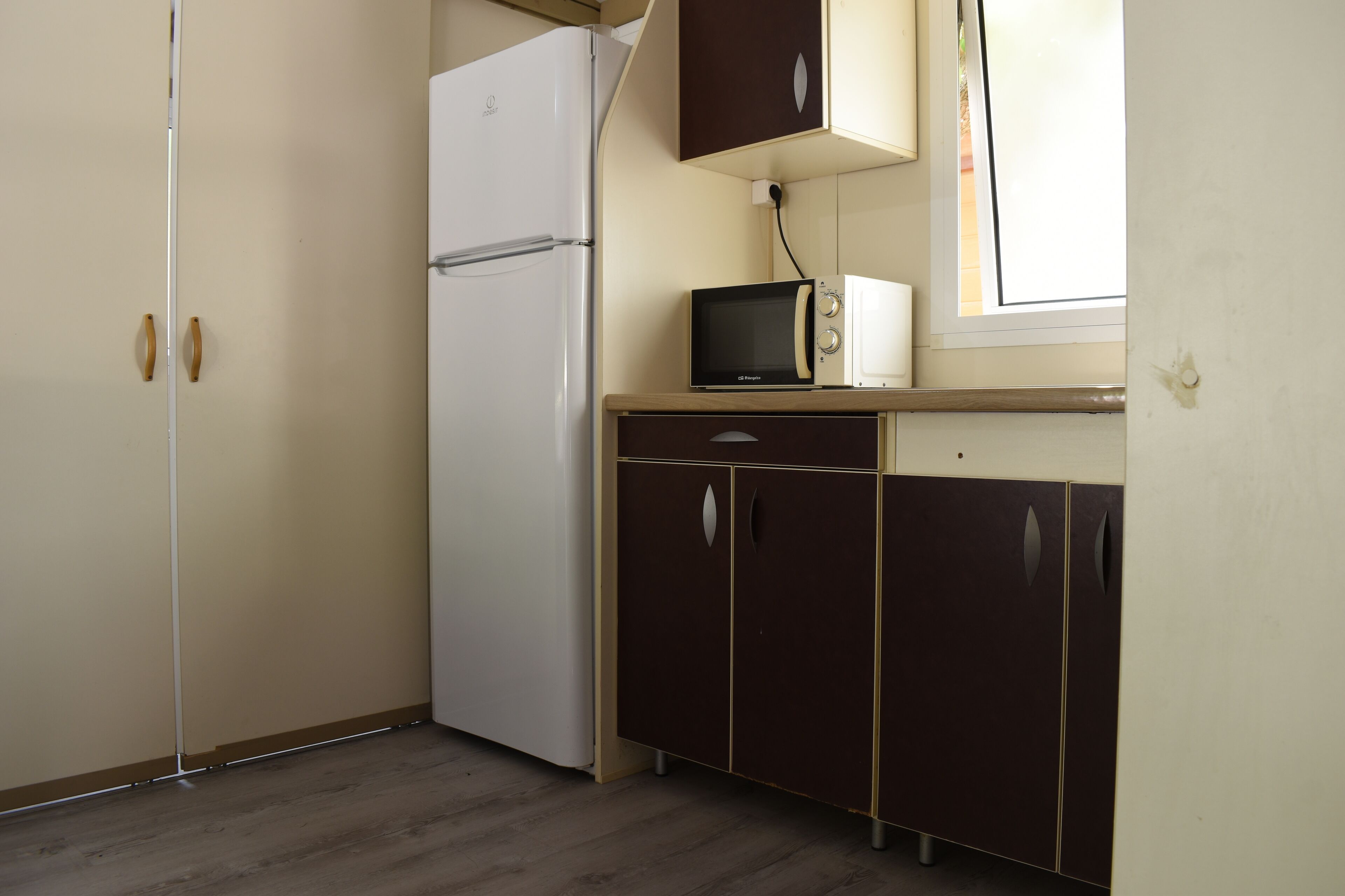 Una cocina compacta con un refrigerador blanco, un microondas y armarios de madera.