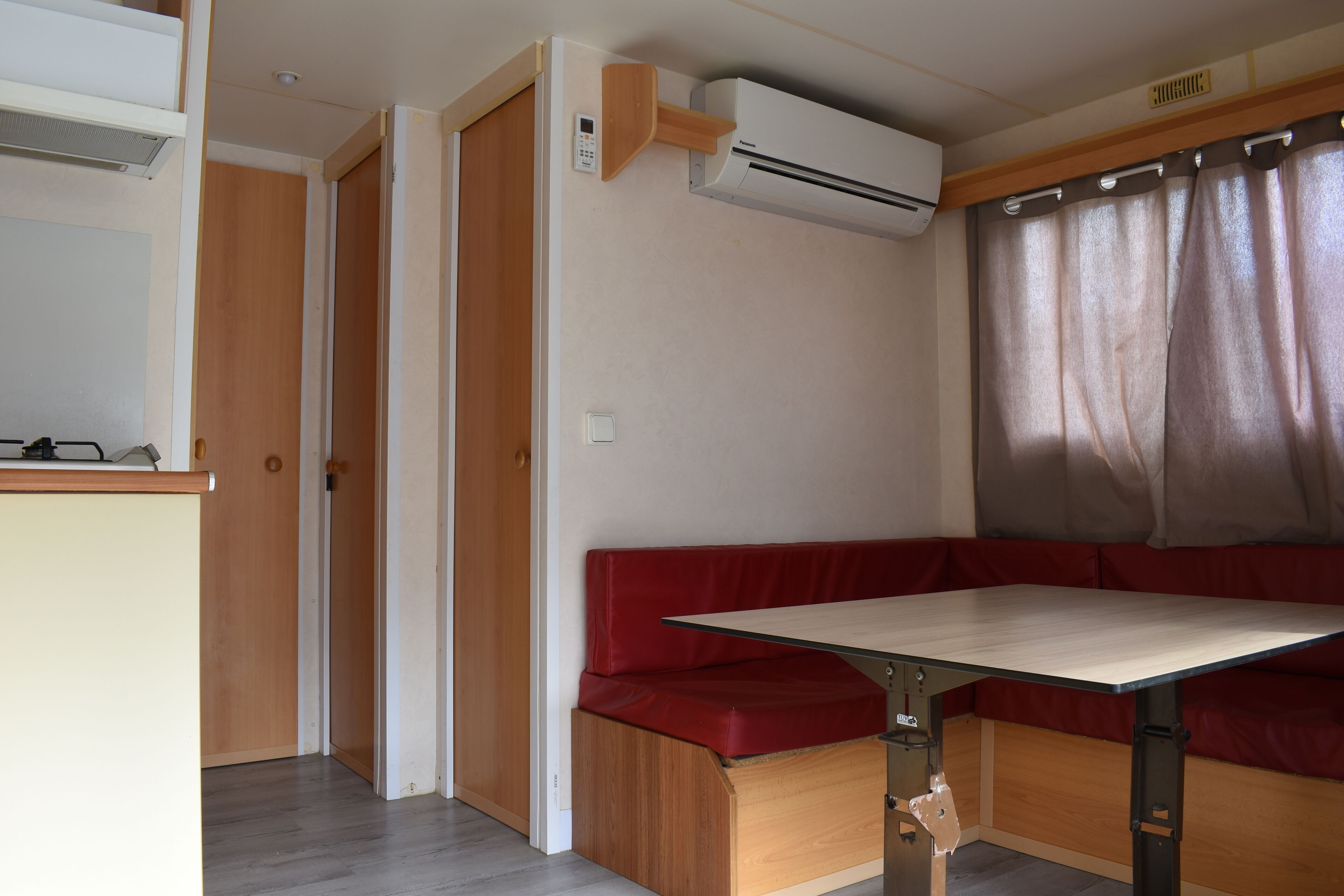 A compact room with a wooden bench, a table, and an air conditioning unit.