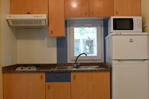 Una cucina con mobili in legno, un forno a microonde, un fornello e un lavello.