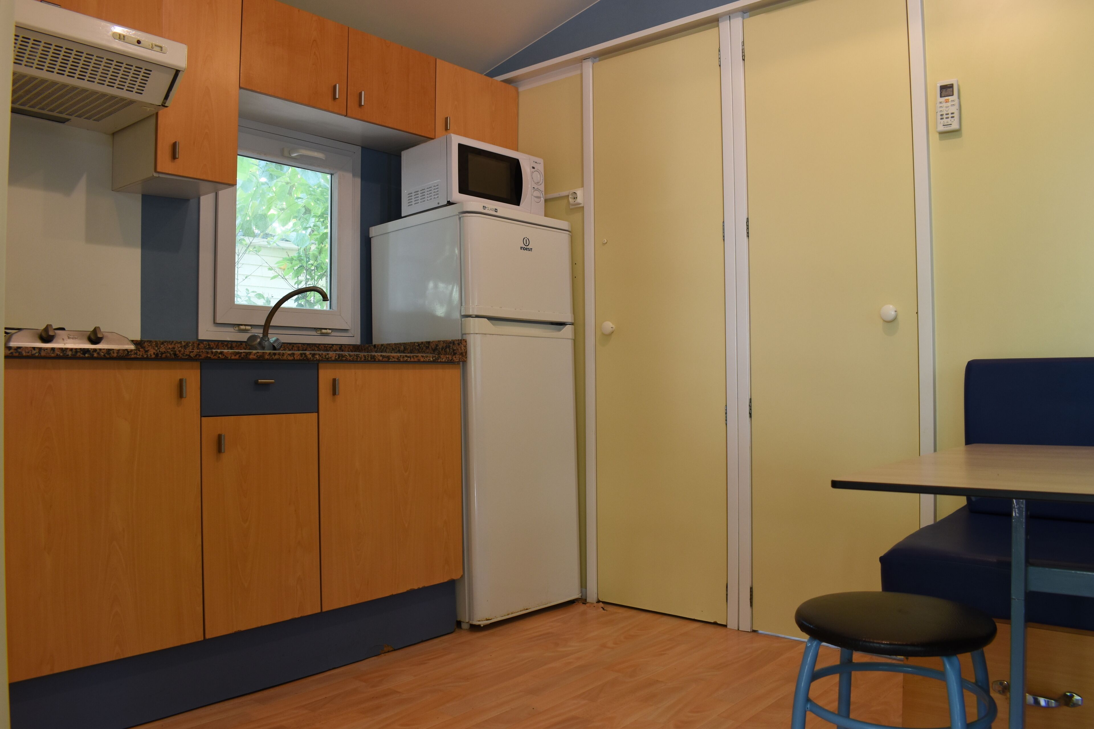 Una cucina compatta con mobili in legno, un forno a microonde e un frigorifero.
