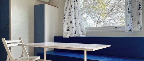 A room with a blue bench, a white table, and a white chair.