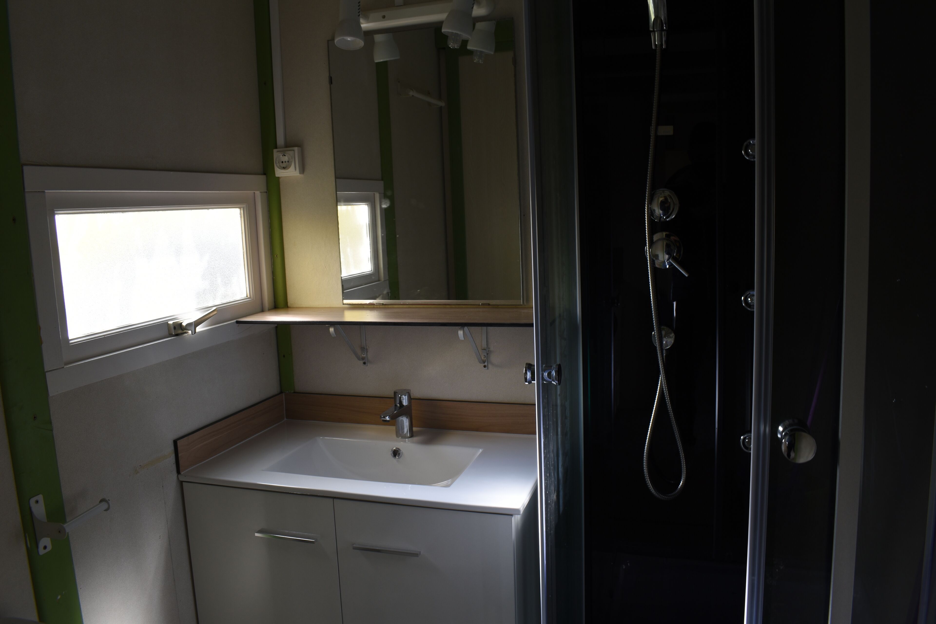 Een kleine badkamer met een wastafel, spiegel en douche.