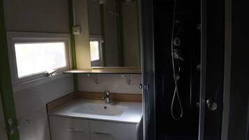 Een kleine badkamer met een wastafel, spiegel en douche.